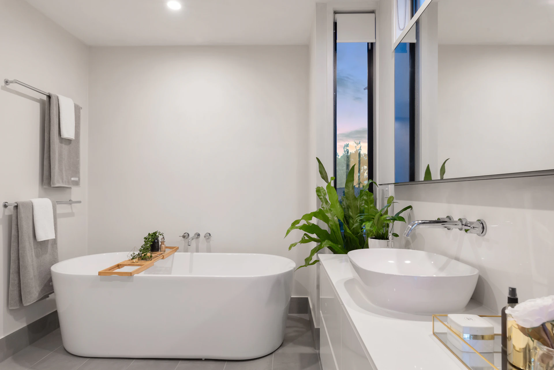 Natural light reflected in a wide bathroom mirror above a white vessel basin