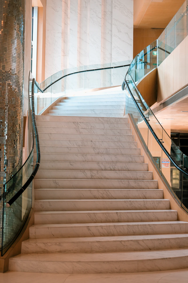 Curved staircase with transparent glass balustrades and dark handrails